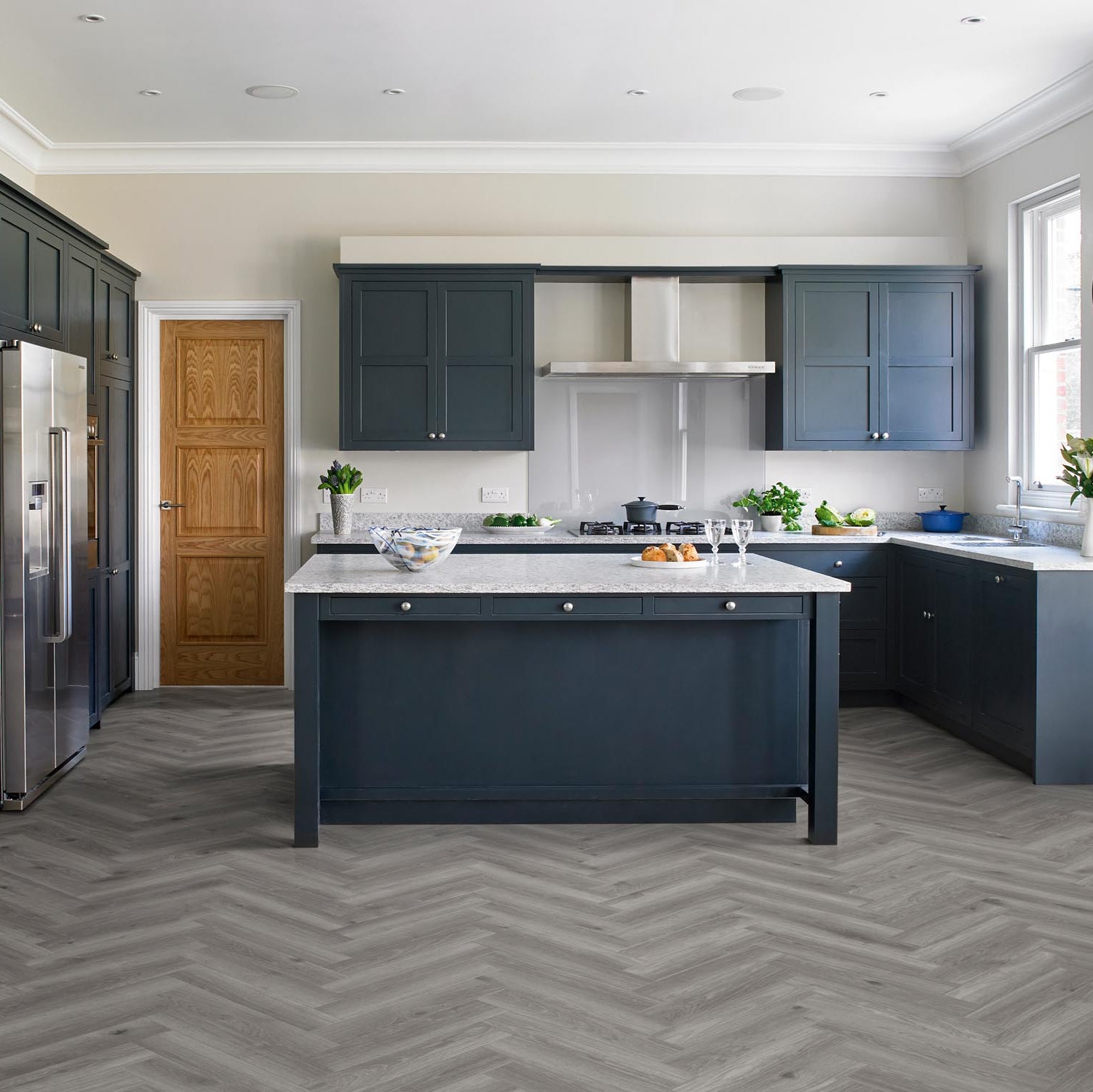 Parquet Timberwolf LVT in a modern kitchen with a central island, featuring grey tones and a classic parquet pattern