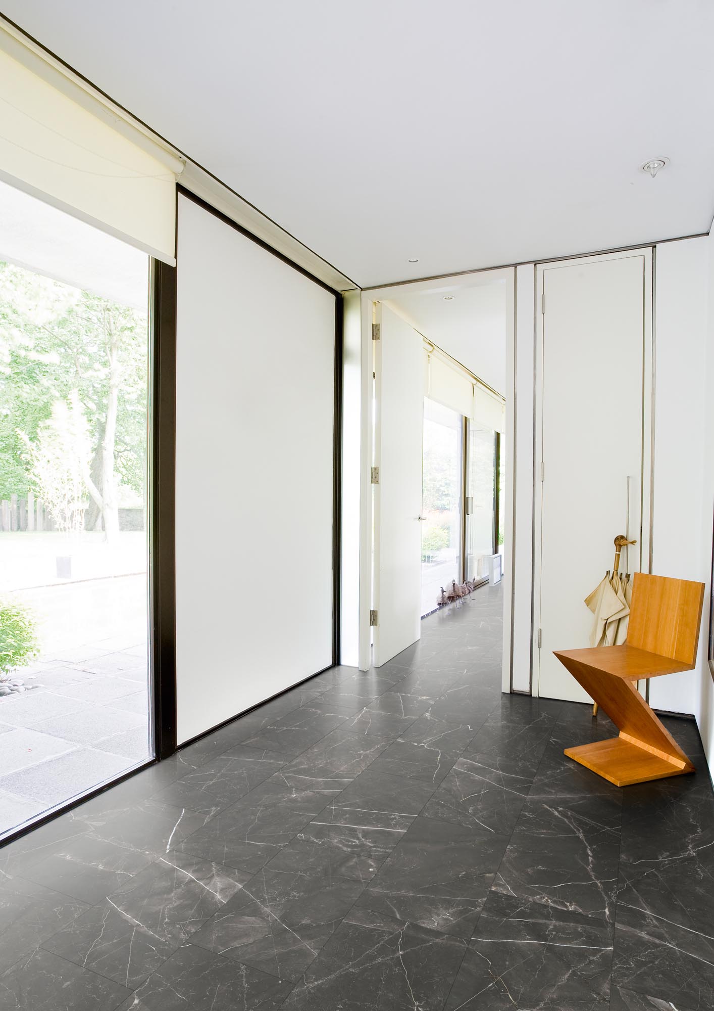 RHINO Evolution LVT in Canterbury Honed Black, showcasing a sleek, black stone effect flooring in a modern hallway with stylish decor.